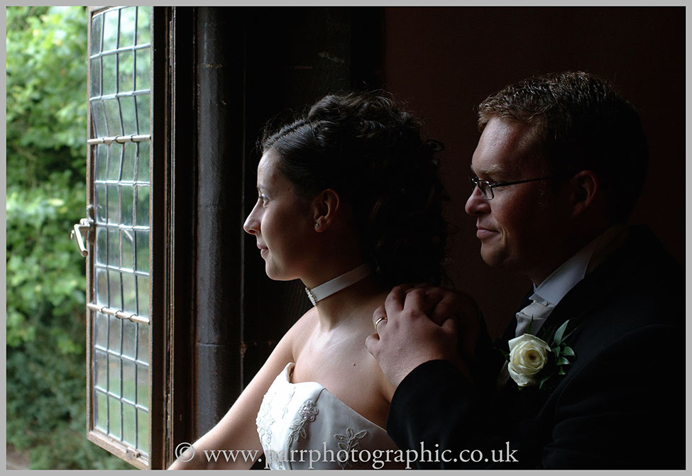 Bride and Groom look out of a old framed window