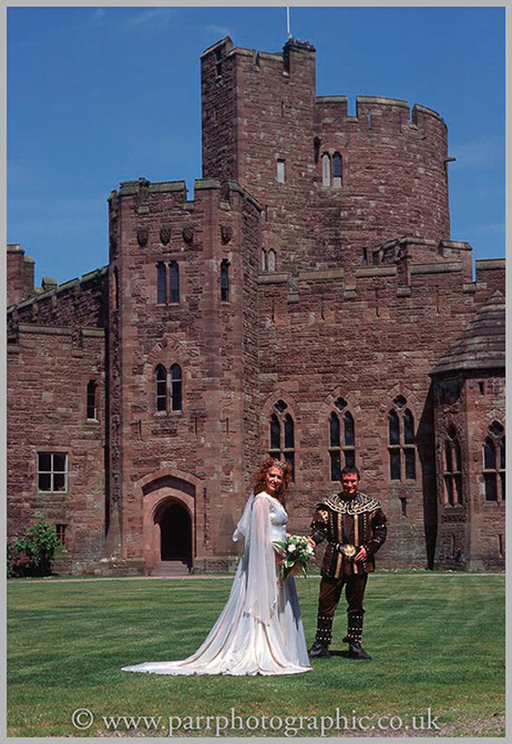 Bride and Groom stand in front of Peckforton Castle Chester