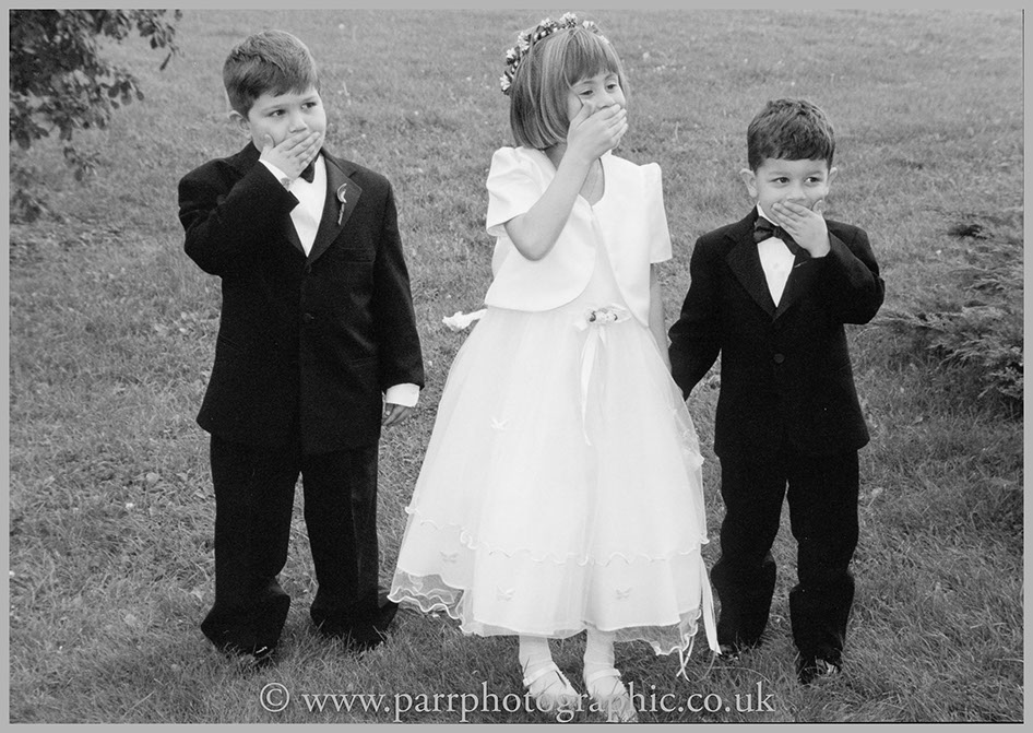 Three children cover their mouths