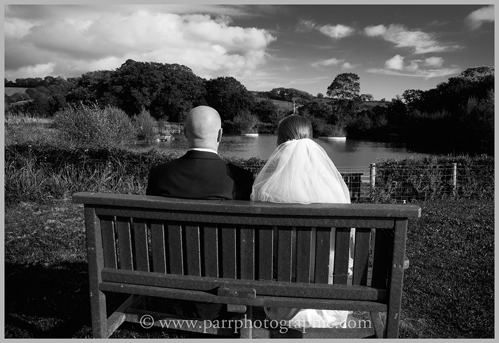 Bride and groom sit looking away on a bench