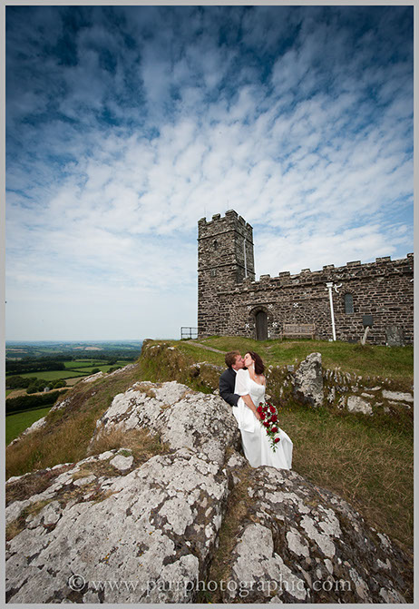 Bride and groom kiss in front of the Brentor Church Devon